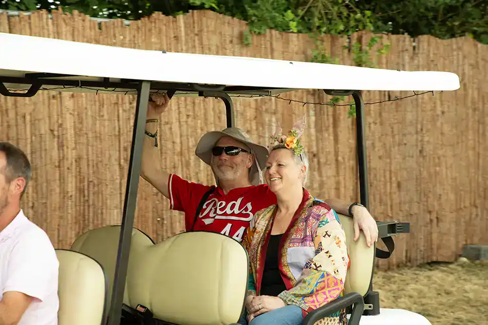 Happy guests riding the complimentary 24-hour private buggy service from the off-site Glastonbury festival glamping grounds to Pedestrian Gate B.